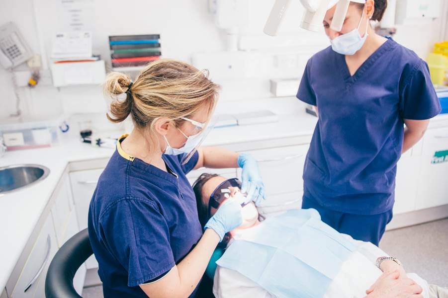 A person in blue scrubs and a mask with a patient in a chair

AI-generated content may be incorrect.