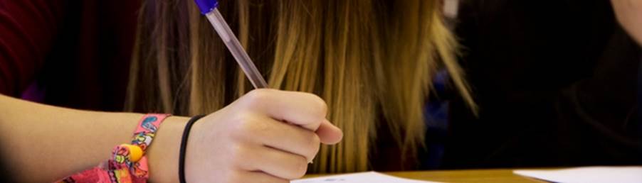 A person writing on a piece of paper
Description automatically generated with low confidence