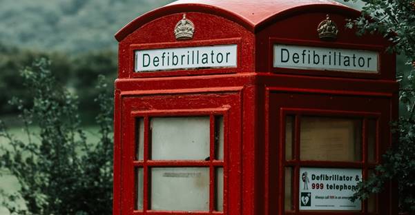 red telephone booth near green tree under white clouds during daytime